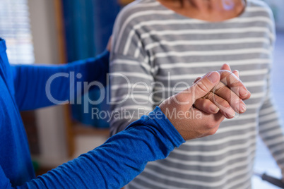 Physiotherapist holding hand of senior patient