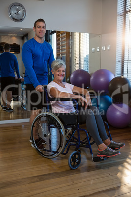 Physiotherapist with senior woman on wheelchair in clinic