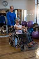 Physiotherapist with senior woman on wheelchair in clinic