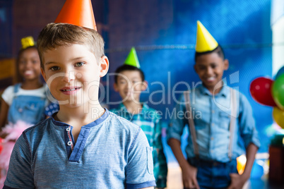 Portrait of boy wearing party hand with friends in background