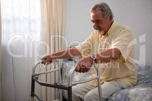 Man holding walker while sitting on bed in nursing home