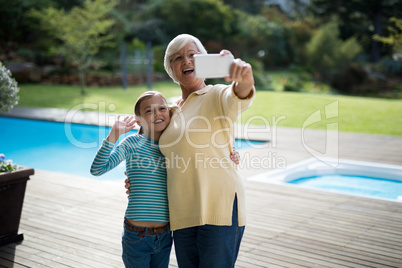 Granddaughter and grandmother taking a selfie near the pool