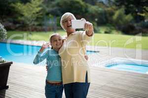Granddaughter and grandmother taking a selfie near the pool