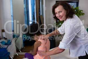 Portrait physiotherapist giving back massage to girl patient