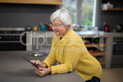 Senior women holding a tablet while standing in the kitchen