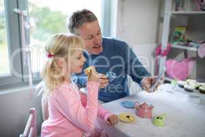Girl and father taking a selfie while playing with a toy kitchen set