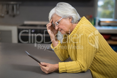 Senior woman using digital tablet in the kitchen