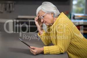 Senior woman using digital tablet in the kitchen