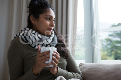 Woman holding coffee cup by window