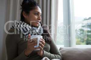 Woman holding coffee cup by window