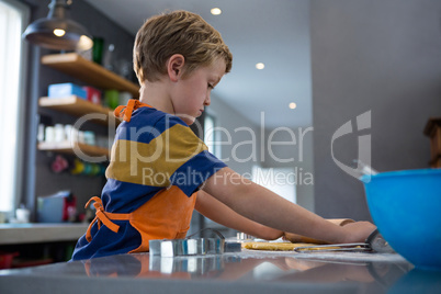 Side view of boy rolling dough