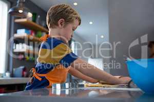 Side view of boy rolling dough