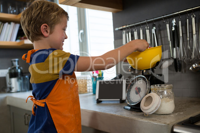 Boy measuring food in bowl over scale