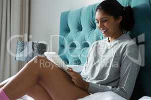 Smiling woman using digital tablet on bed