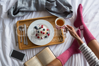 Low section of woman having breakfast on bed