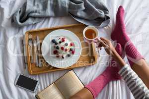 Low section of woman having breakfast on bed