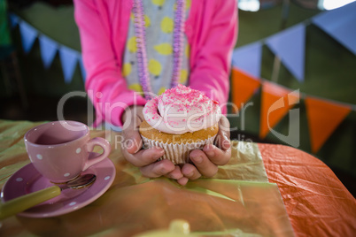 Birthday girl holding a cupcake at home