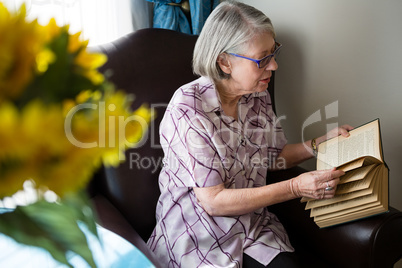 Senior woman reading book while sitting in nursing home