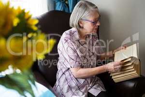 Senior woman reading book while sitting in nursing home