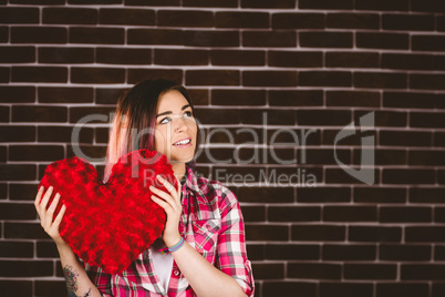 Thoughtful woman holding heart shape