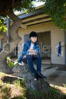 Girl sitting on tree trunk near stable