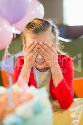 Cute girl covering her eyes during birthday party