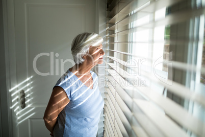 Senior woman looking through window in bedroom