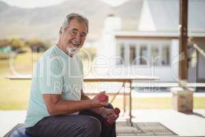 Smiling senior man exercising with dumbbells