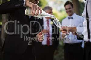 Groom pouring champagne into his friends glasses