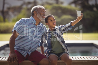 Grandson and grandfather taking selfie with mobile phone