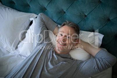 Smiling man sleeping on bed in bedroom