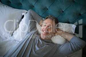 Smiling man sleeping on bed in bedroom