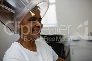 Senior woman sitting under hair steamer