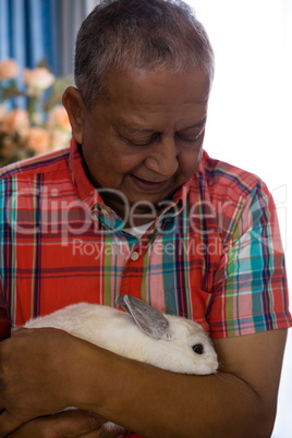Senior man holding rabbit at retirement home