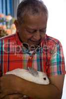 Senior man holding rabbit at retirement home