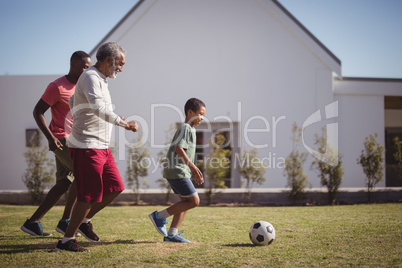 Boy playing football with his father and grandson