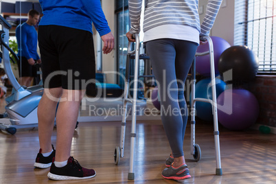Physiotherapist assisting patient to walk with walking frame