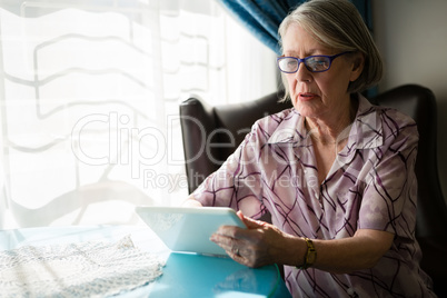 Senior woman using digital tablet while sitting in nursing home