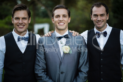 Smiling bridegroom and best man standing in garden