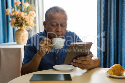 Senior man using digital tablet at table in nursing home