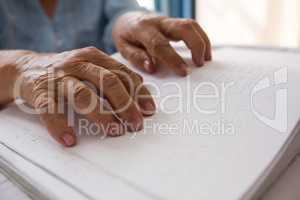 Hands of senior woman reading braille in nursing home
