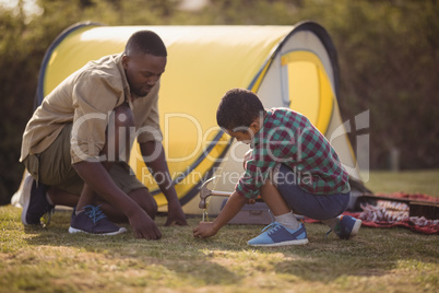 Father and son pitching their tent in park