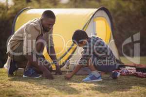 Father and son pitching their tent in park