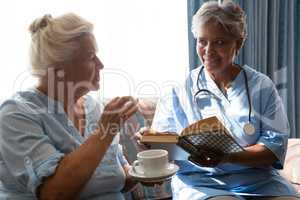 Woman talking to doctor holding book in nursing home