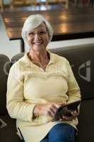 Smiling senior woman using digital tablet on sofa