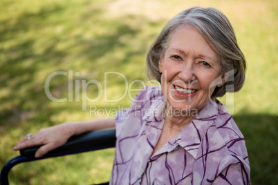 Portrait of happy senior woman sitting on wheelchair at yard