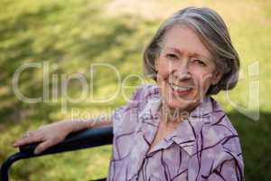 Portrait of happy senior woman sitting on wheelchair at yard