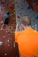 Trainer assisting boy in rock climbing