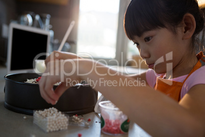 Girl decorating cake at home