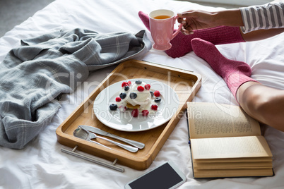 Low section of woman doing breakfast on bed